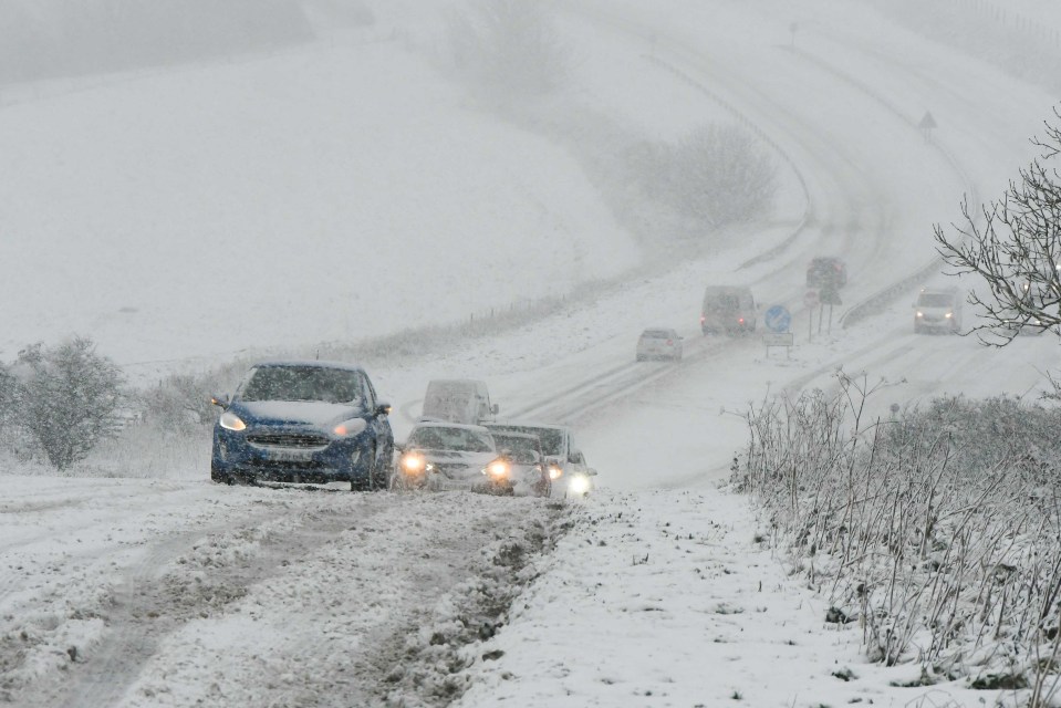 a blue ford car is driving down a snowy road