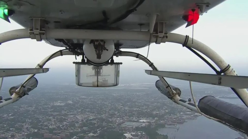 a helicopter is flying over a city with a red light on the side