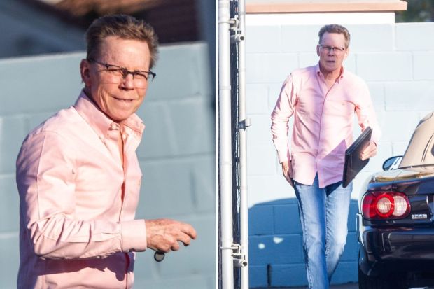 a man wearing glasses and a pink shirt is walking