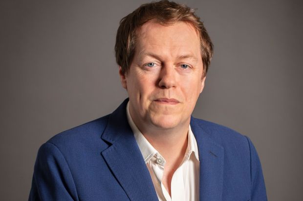 a man in a blue jacket and white shirt looks at the camera