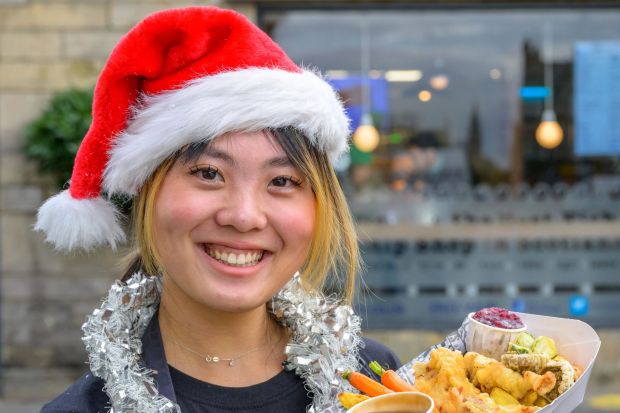 a woman wearing a santa hat holds a plate of food