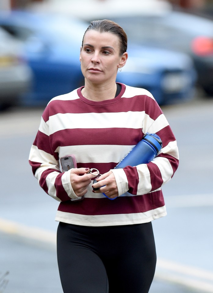 a woman in a striped shirt holds a yoga mat and a cell phone