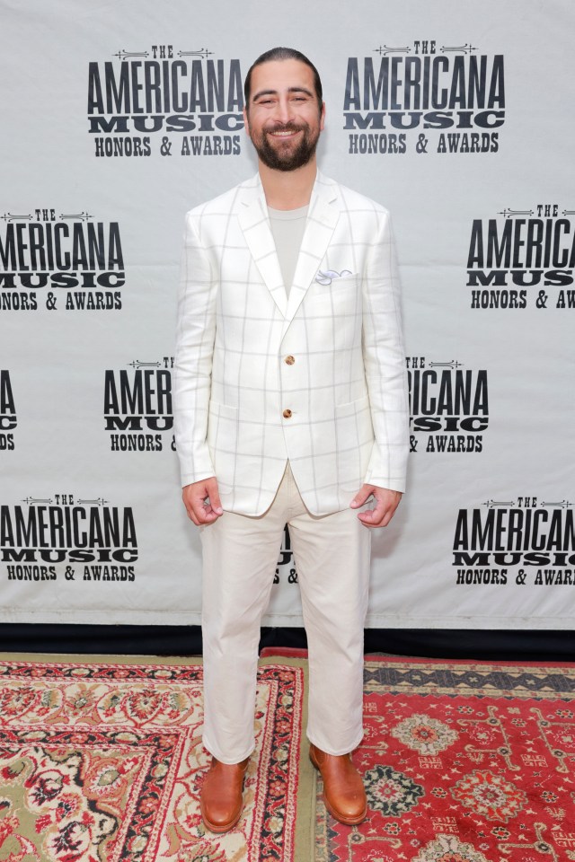 a man stands in front of a wall that says the american music honors & awards