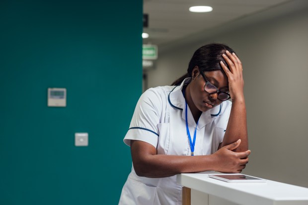 a nurse leaning on a counter with her hand on her head