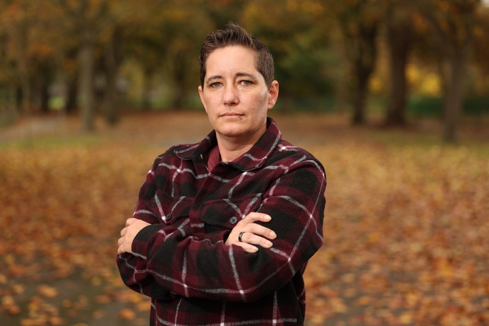 a woman in a plaid shirt stands with her arms crossed