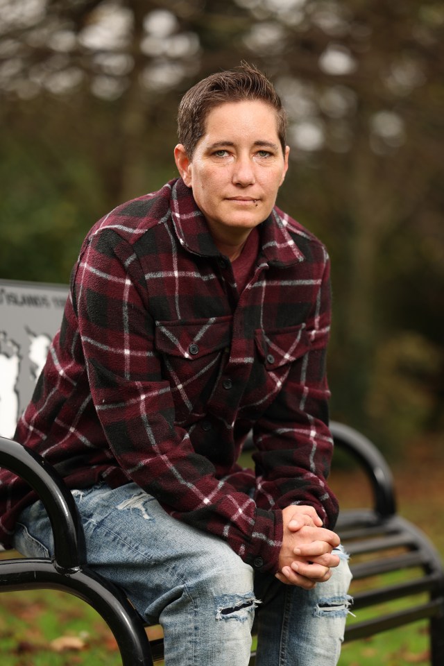 a woman in a plaid shirt sits on a park bench