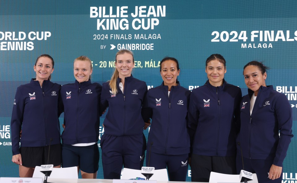 a group of women standing in front of a sign that says billie jean king cup