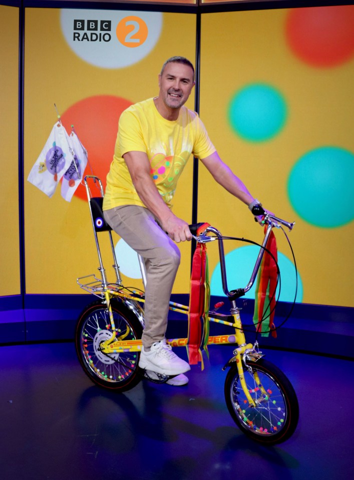 a man is riding a bicycle in front of a bbc radio 2 sign