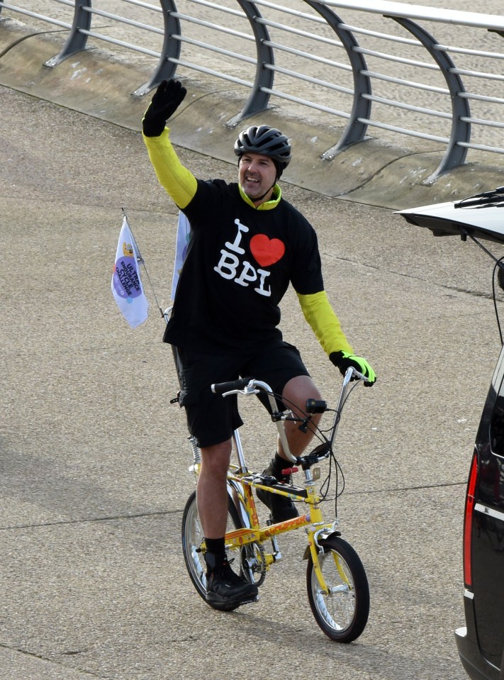 a man wearing a shirt that says i heart bpl is riding a bike