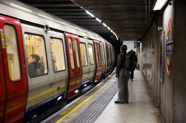 a man stands on a platform waiting for a subway train