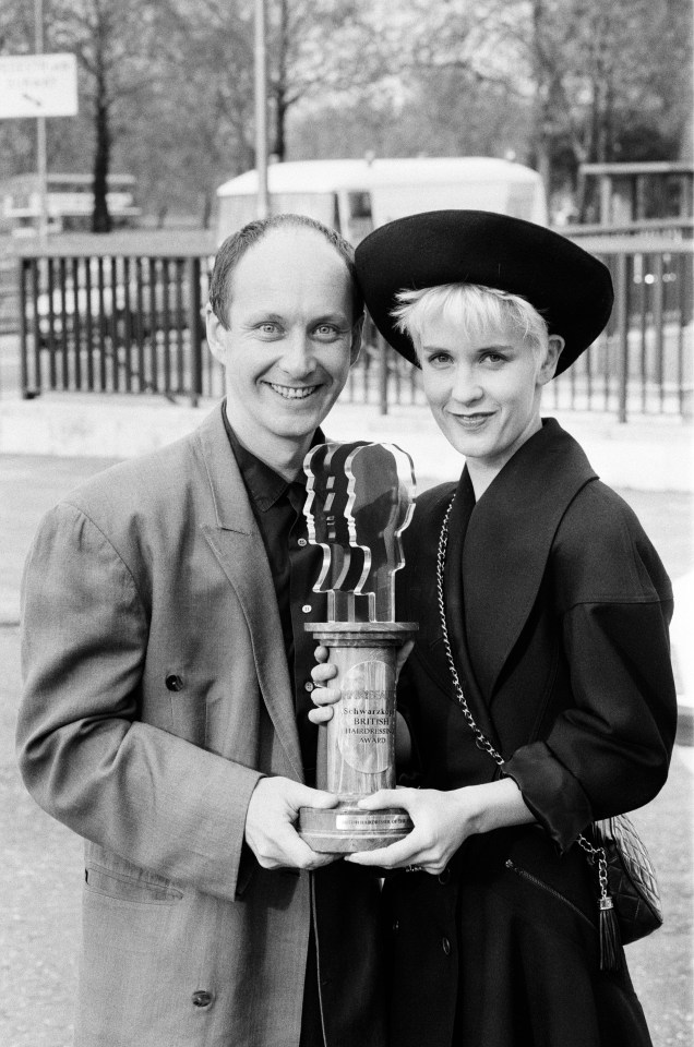 a black and white photo of a man and woman holding a trophy