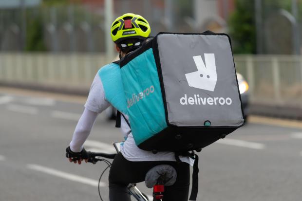 a person riding a bike with a deliveroo bag on their back