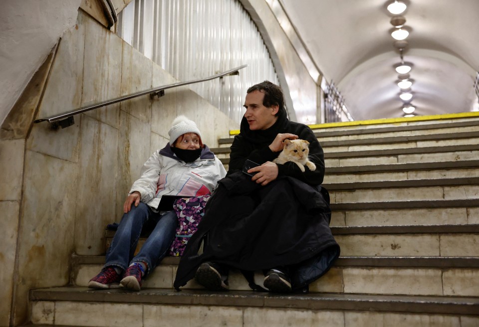 A man cuddles with his cat as they take shelter