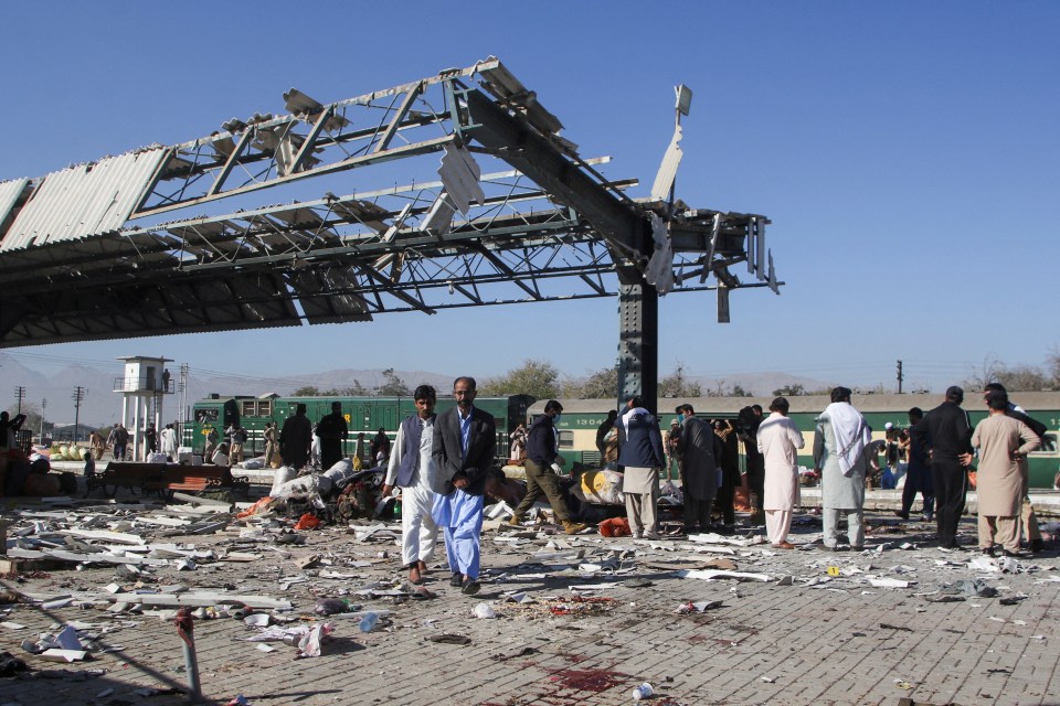 People walk amid the debris after a bomb blast at a railway station in Quetta, Pakistan