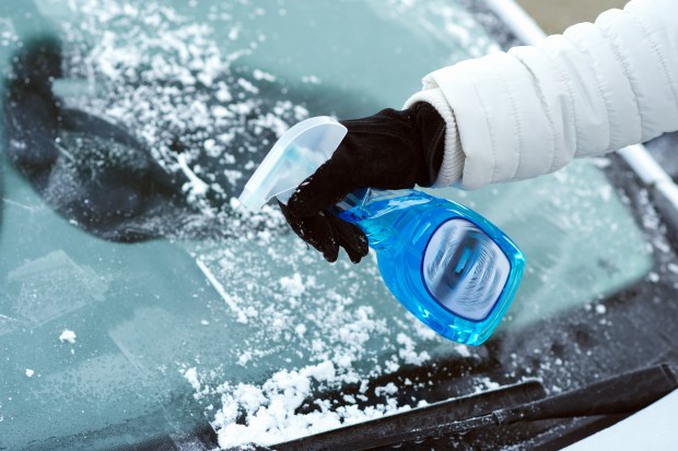 a person cleaning a car windshield with a spray bottle