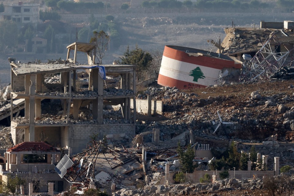 An Israeli flag (L) on a destroyed building, and a Lebanese flag (R) painted on a damaged building in the southern Lebanese village of Meiss El-Jabal on Sunday