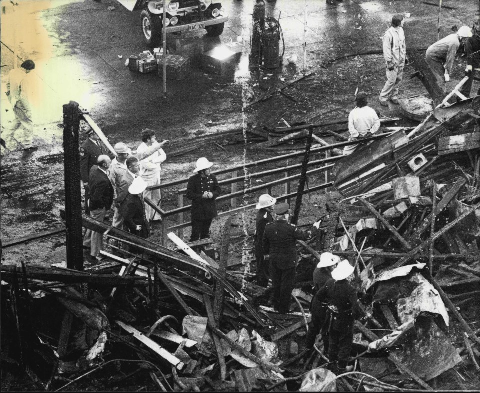 a black and white photo of a group of people standing around a pile of rubble