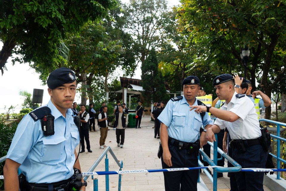 a police officer stands in a park with his arms outstretched