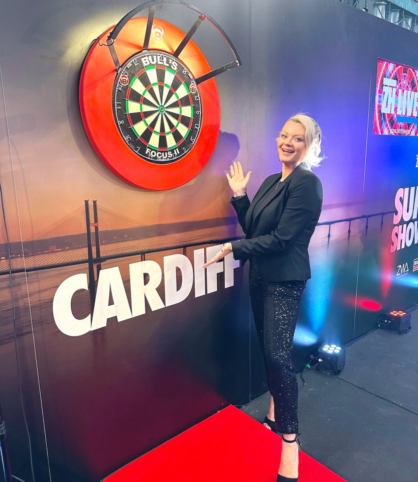 a woman stands in front of a bull 's eye dart board