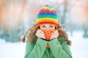 a woman wearing a colorful hat and scarf covering her face in the snow