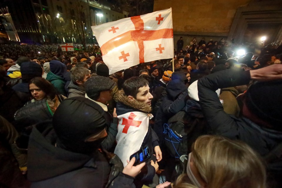 Protesters with a Georgian national flag pour into the streets