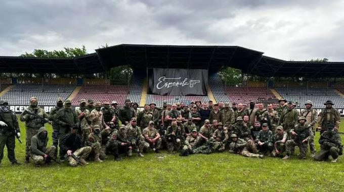 a group of soldiers are posing for a picture in front of a stadium .