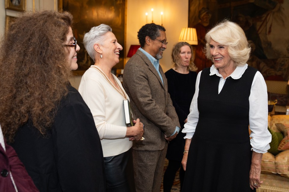 a group of people are standing around a woman in a black dress