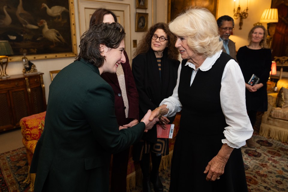 a woman in a green jacket shakes hands with a woman in a white shirt