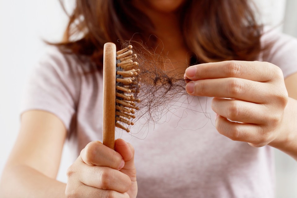 a woman is holding a brush full of hair