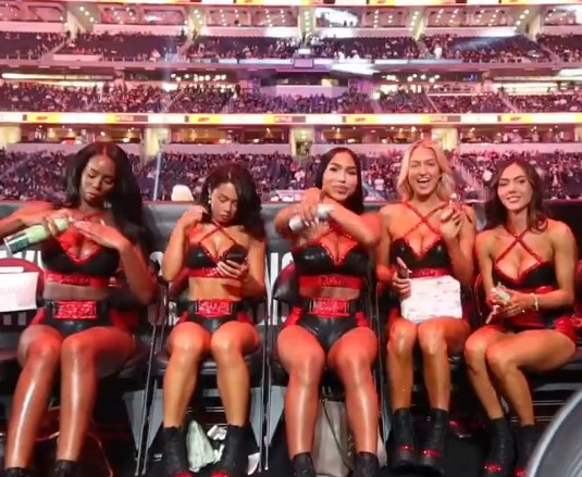 a group of women are sitting in chairs in a stadium looking at their phones .