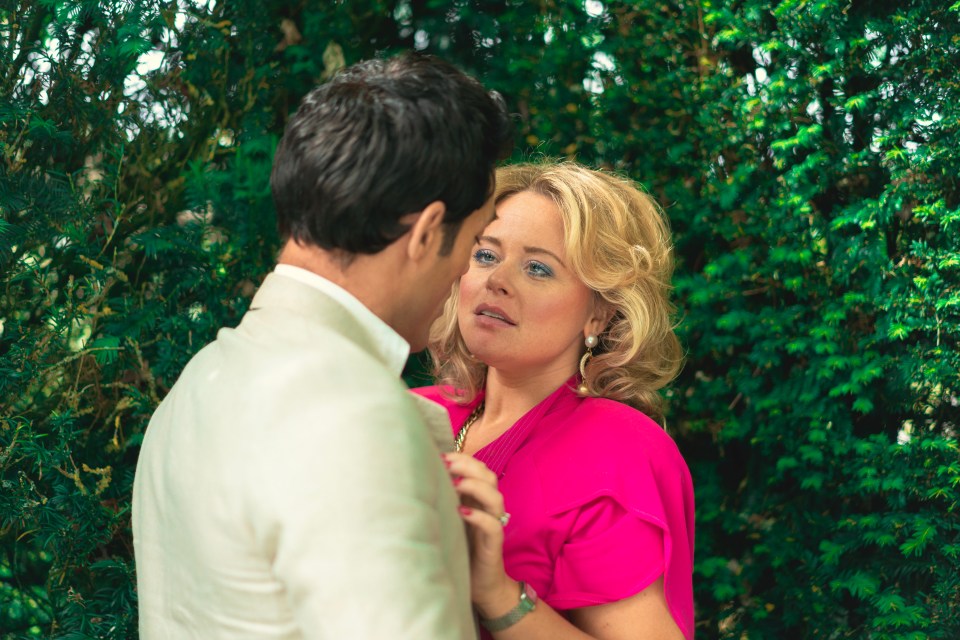 a woman in a pink shirt is looking at a man in a white suit