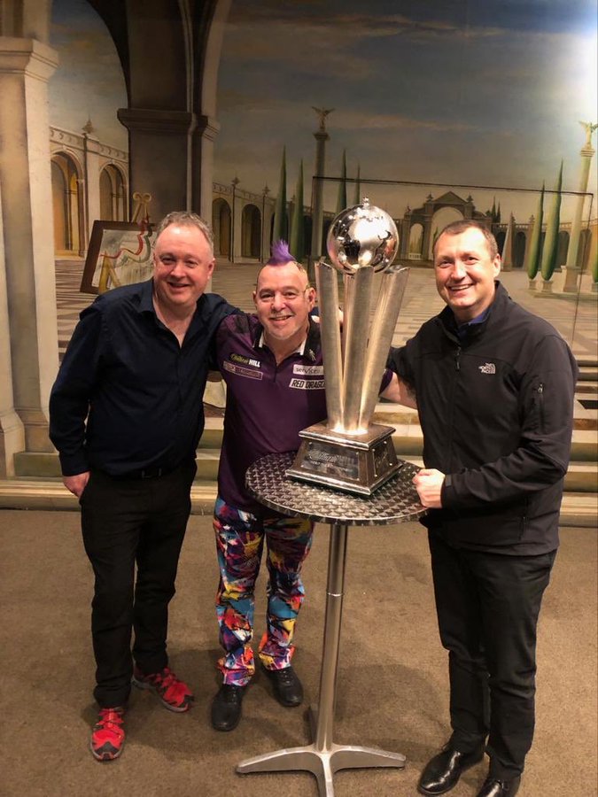 a man with a mohawk stands between two men holding a trophy