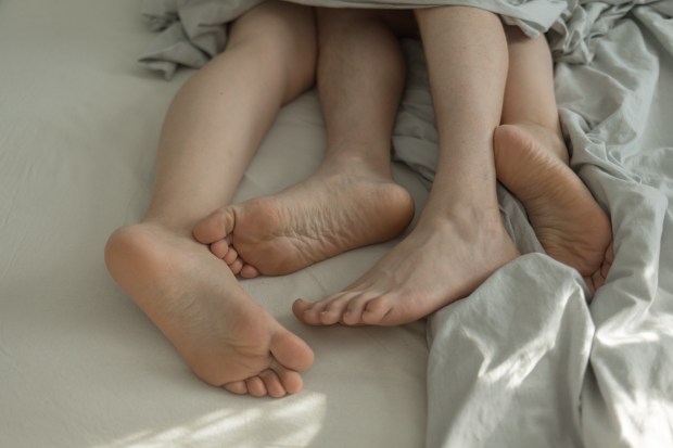 a couple laying on a bed with their feet crossed