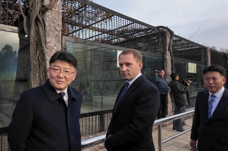 a man in a suit and tie stands in front of a cage