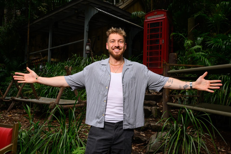 a man with his arms outstretched in front of a red telephone booth