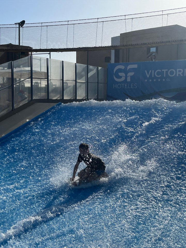 a person riding a wave in front of a sign that says gf hoteles