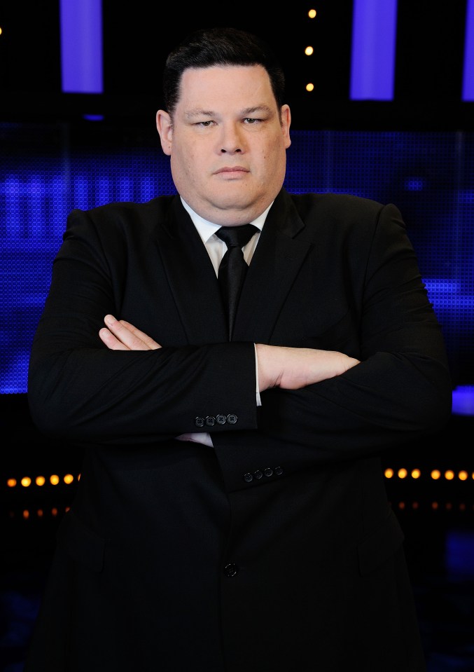 a man in a suit and tie stands with his arms crossed