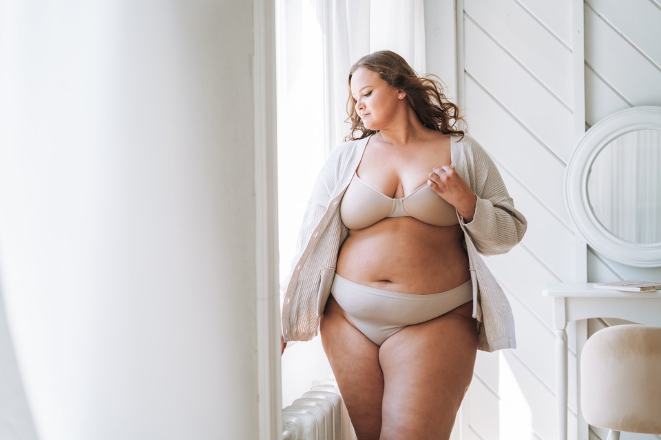 a woman in lingerie is standing in front of a window