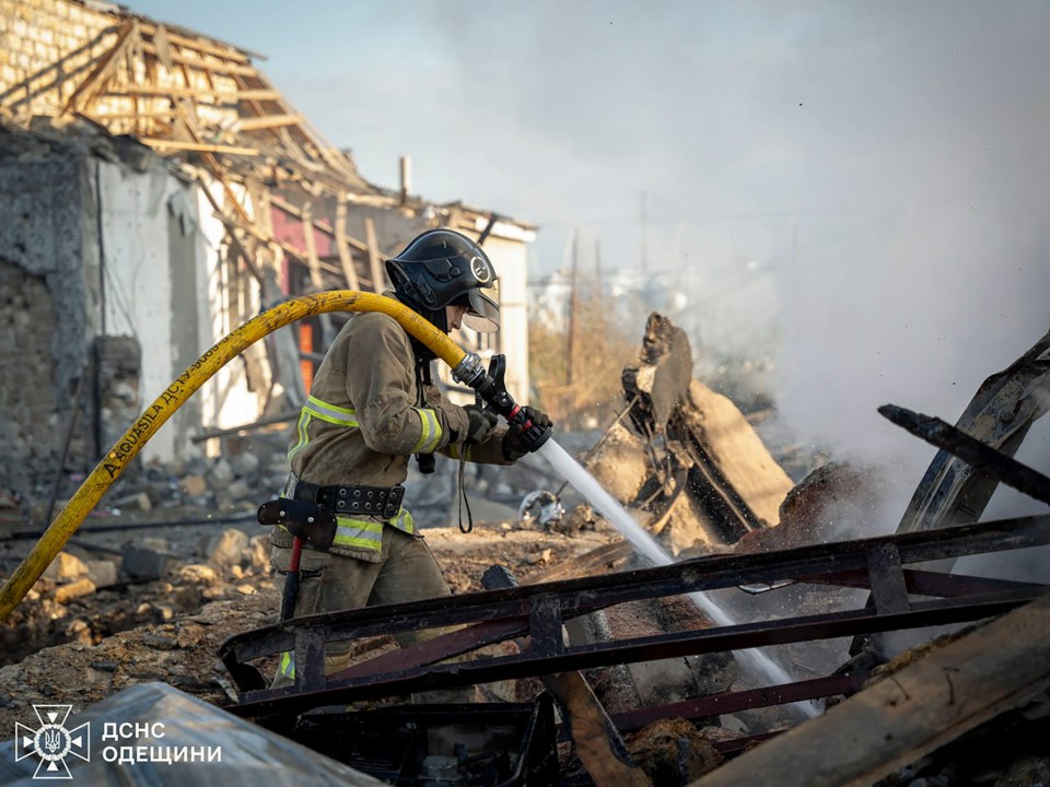 A firefighter works to put out flames from crumbling buildings following a Russian attack