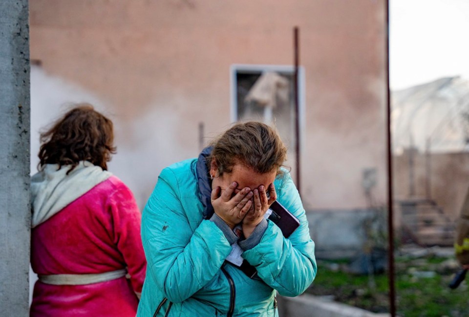 a woman in a blue jacket covering her face with her hands