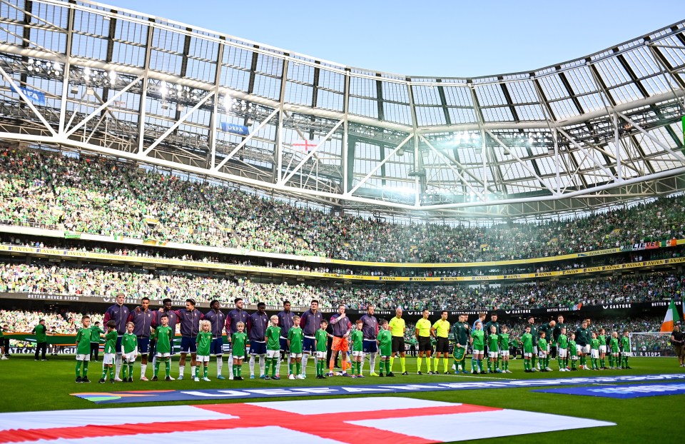 soccer players stand on a field in front of a stadium that says ' aston martin ' on it