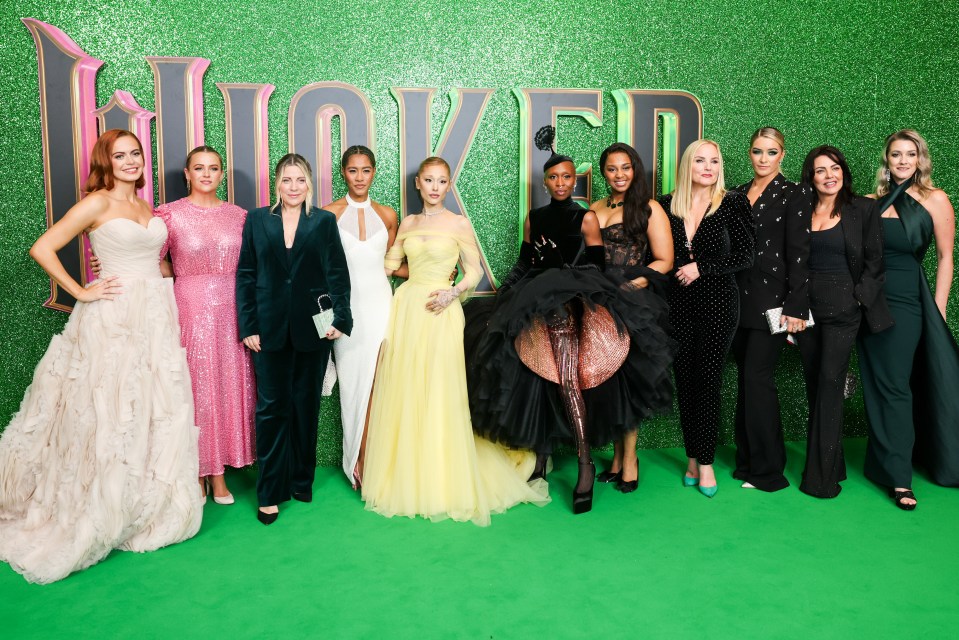 a group of women pose for a picture in front of a sign that says wicked