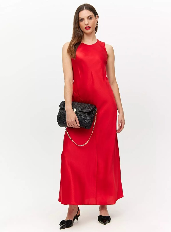 a woman in a red dress is holding a black bag