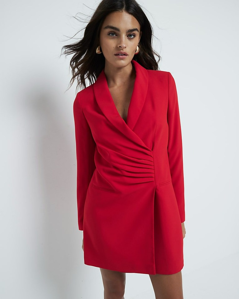 a woman is wearing a red blazer dress