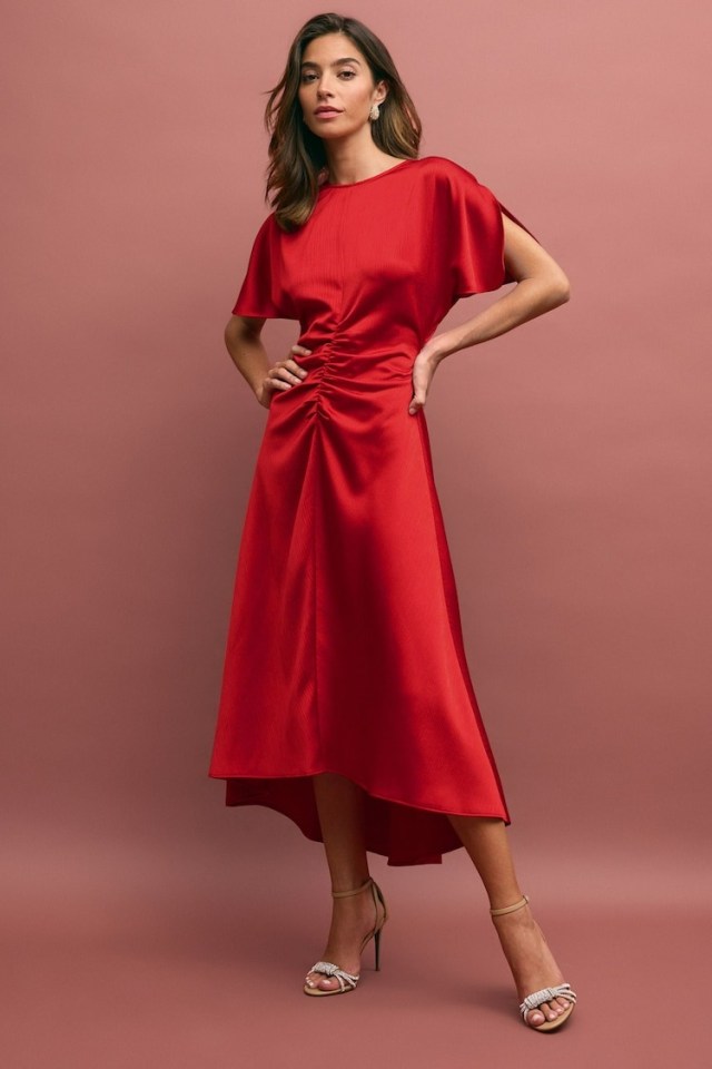 a woman is wearing a red dress and heels