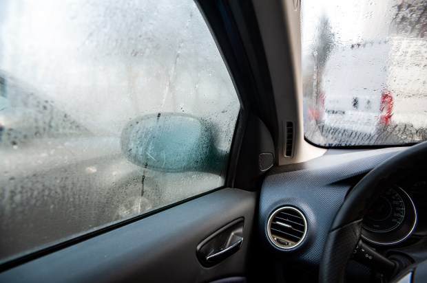 a person cleaning a car window with a black cloth