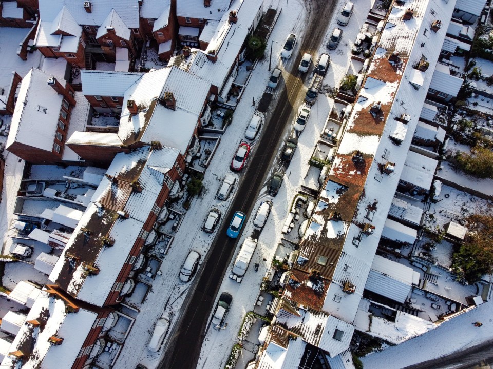 an aerial view of a snowy street with houses and cars