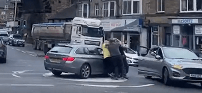 a group of people are trying to get out of a car .