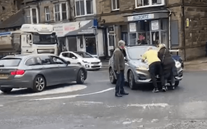 a man in a yellow shirt is cleaning the windshield of a car .