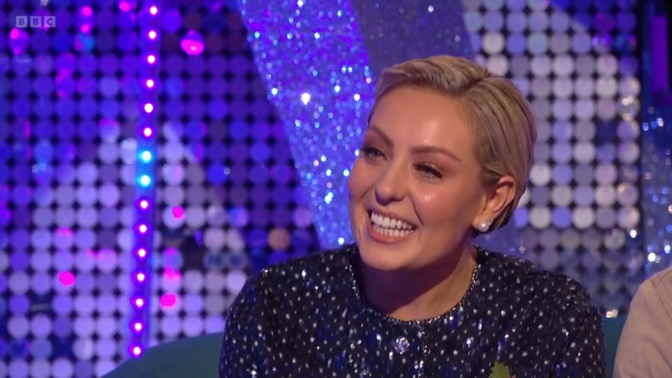 a woman is smiling in front of a bbc logo